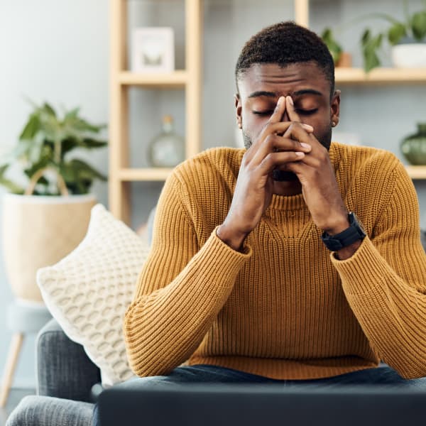 Man in yellow jumper, look a little stress with his head in his heads.
